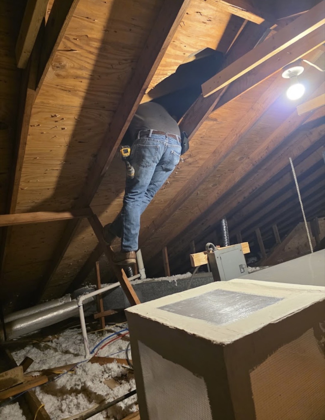 Crew member working in an attic space during a roofing service call